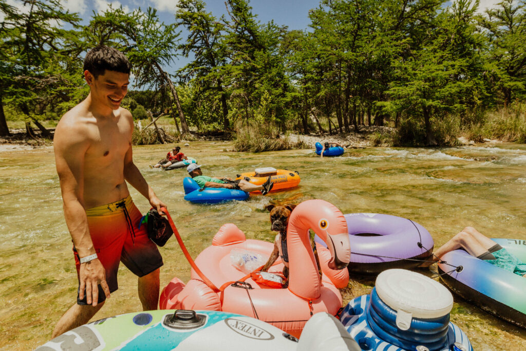 A man and his dog tubing and enjoying one of Frio Country Resort's pet-friendly vacation rentals on the Frio River.
